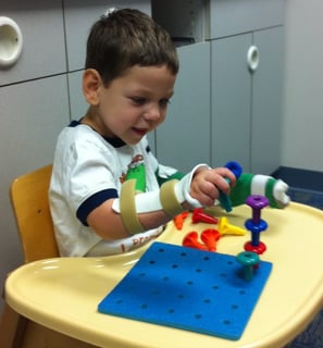 um menino sentado em uma mesa com um brinquedo