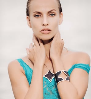 A close-up of a woman with wet, with accessorized with a black star-themed bracelet, necklace