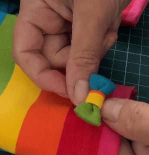 a person is making a rainbow - coloured bow to attach to leggings
