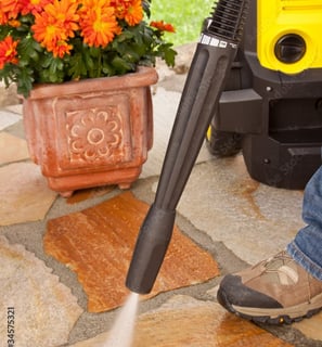a person using a pressurer to clean a patio