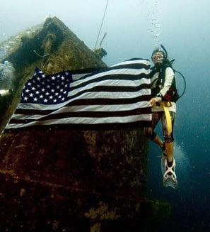 a scuba diver with a flag on a rock formation