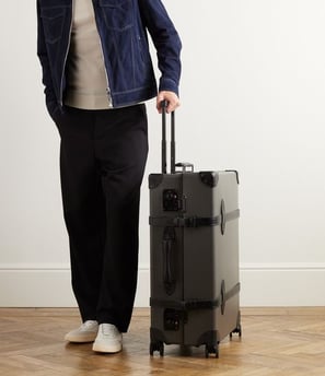 a man in a jacket and pants standing next to a suitcase