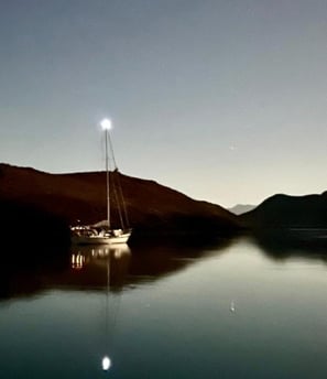 a sailboat in the water with a bright light shining on the water