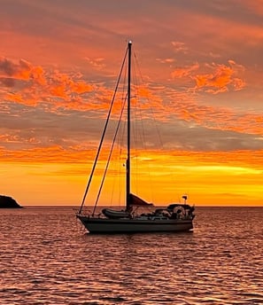 a sailboat in the ocean at sunset