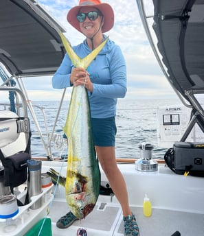 a woman in a hat and sunglasses holding a fish