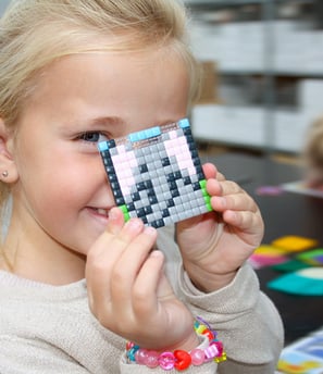 Happy girl showing the picture of an elephant made of colorful silicone pixel squares