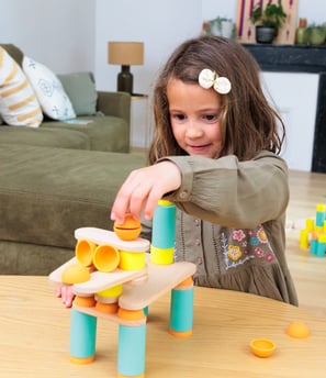 The girl is creating a unique construction from colorful silicone and wooden figures