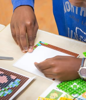 Human creating a picture with hands using transparent baseplate and colorful pixel squares