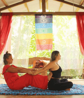 two women in red dresses are sitting on a mat