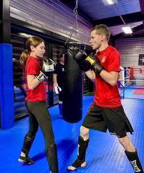 Entraînement de boxe : un homme et une jeune fille en garde, prêts à boxer