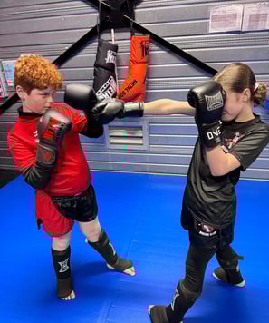 Boxe éducative : une jeune fille enchaîne des coups de poing face à un garçon en garde