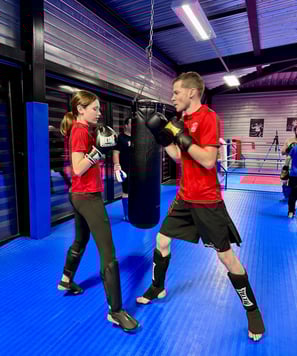 Entraînement de boxe : un homme et une jeune fille en garde, prêts à boxer