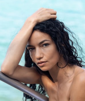 portrait d’une femme au teint doré, regard intense et captivant fixé vers l’appareil photo