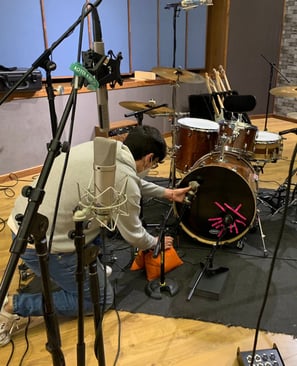 a man is playing drums in a recording studio