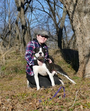 woman kneeling next to bully breed mix. 