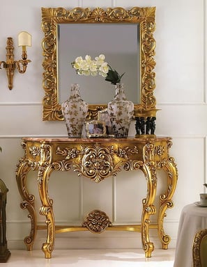 a gold console table with a mirror and a vase with flowers