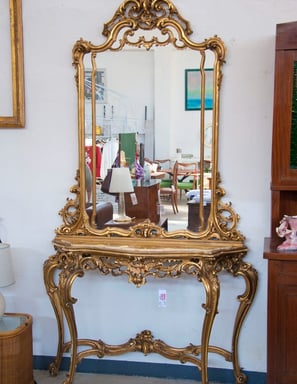 a gold console table with a gold frame and a mirror