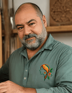 Artesano de Aretística sostiene un cuadro de madera tallado a mano en su taller, mostrando el proces