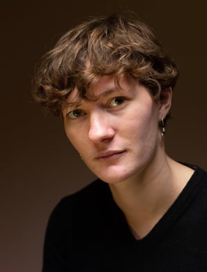 Personne aux cheveux courts et à l'air sérieux sur un fond marron