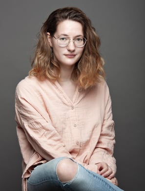 Une femme avec une chemise rose et un jean sur un fond gris