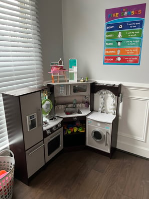 Photo of daycare room where children play. Small toy kitchen.