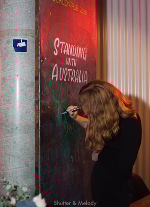 Eine Frau gestaltet ein Schild "Standing with Australia".