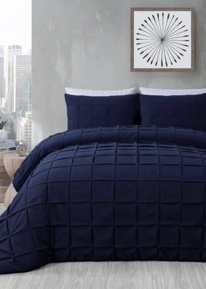 a bed with a blue comforter and a clock on the wall