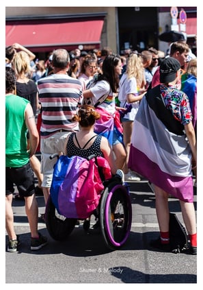 Eine Frau in einem Rollstuhl mit einer bisexuellen Fahne.