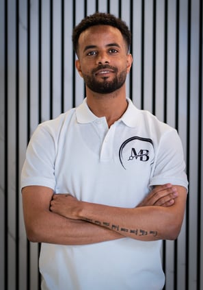 well lit Portrait photo of Ben, Co-owner of MB Barbers Manchester, posing with a smile and his arms crossed