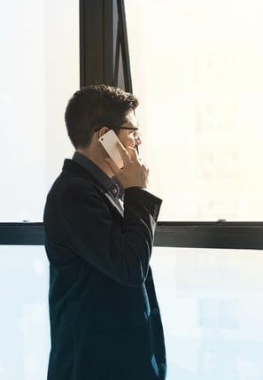 Uomo al cellulare che guarda fuori dalla finestra