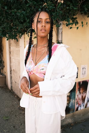 portrait d'une femme noire avec brassière colorée et pantalon ample blanc