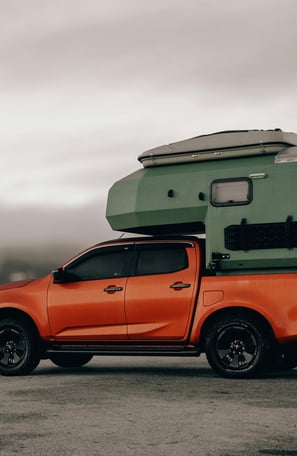 Orange Suzuki Pick-Up with camping gear