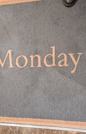 Three feet on a rug that says "Monday"