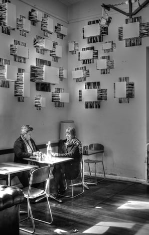 Peter Pickering snaps two ladies sitting at a table with drinks in a trendy cafe.