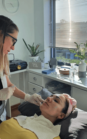 a woman getting a facial lift from a woman in a white shirt Dra. Flavia Ward