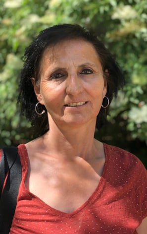 Portrait de Muriel Renucci, avec un fond végétal flou, créant une atmosphère naturelle et apaisante