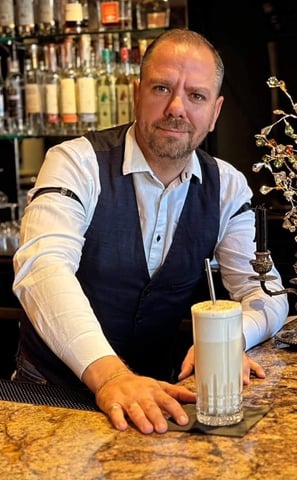 a man in a vest and vest is holding a drink