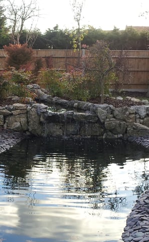 a pond with rockery stone and water in the foreground