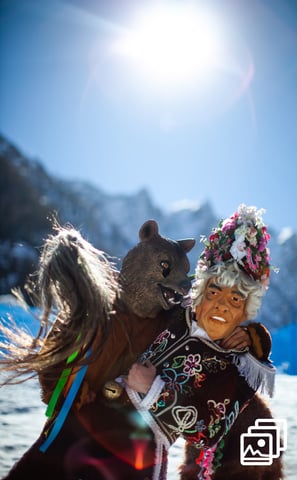a man in a costume with a bear during carnival in winter