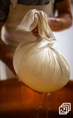 a person holding a bag of milk in a cheese factory
