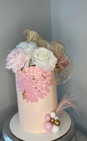 a cake with a pink and gold flower arrangement