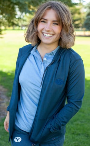 a woman in a blue jacket and jeans standing in a field