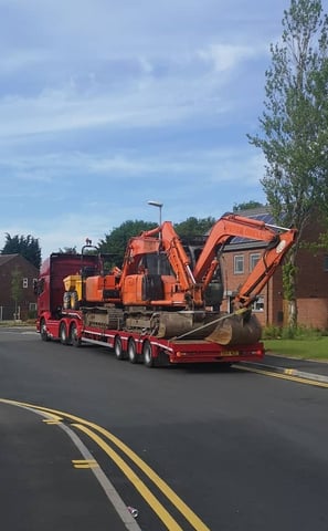 digger on the back of a lorry in a street in stourbridge