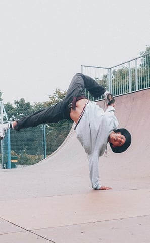 YoYo performing a breakdance freeze in a skateboard park.