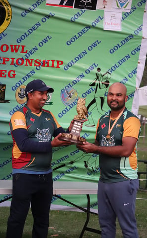 a man holding a trophy in front of a banner