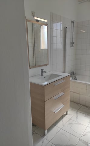 installation dans une salle de bain d'un nouveau lavabo avec son meuble, miroir et éclairage