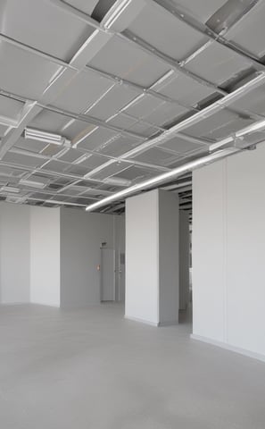 A white wall with two vent openings casting shadows. There is a yellow caution sign with Chinese characters and a telephone number, along with a small mailbox or utility box attached to the wall.