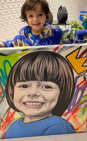 Imagem de uma criança feliz, segurando uma pintura do seu rosto.