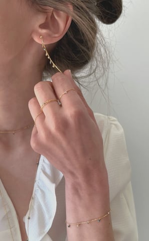 Photo bijoux BYNORA portés. Chaîne d'oreilles, bagues, sautoir et bracelet avec des diamants bruts multicolors
