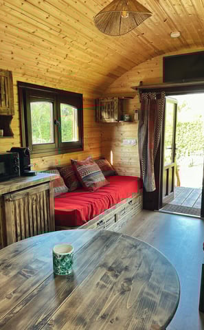 Intérieur de la roulotte avec un des jolis canapé en bois, télé, table à mangé